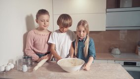 Three beautiful children help in the kitchen and prepare the dough.