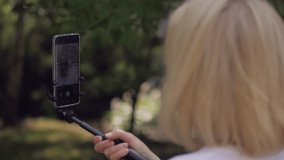 A woman using a smartphone is broadcasting live while walking in a city Park