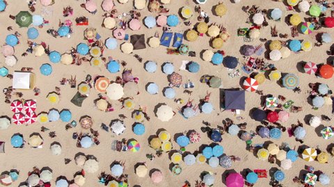 Top down aerial timelapse view of colourful sun umbrellas and people relaxing at the beach in Rio de Janeiro, Brazil, fun tropical vacation and summer background. 