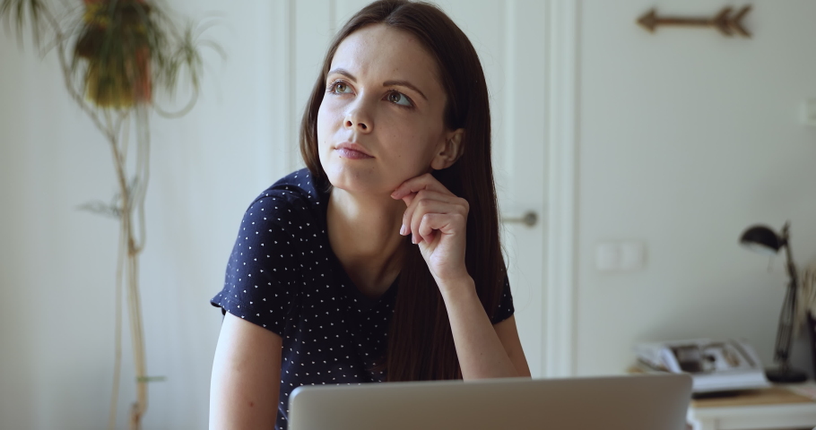 Thinking student girl sits in front of laptop make task, look into distance feels doubtful, deep in her thoughts, comes up with solution find answer texting on pc. Brain work, study process concept Royalty-Free Stock Footage #1055702594