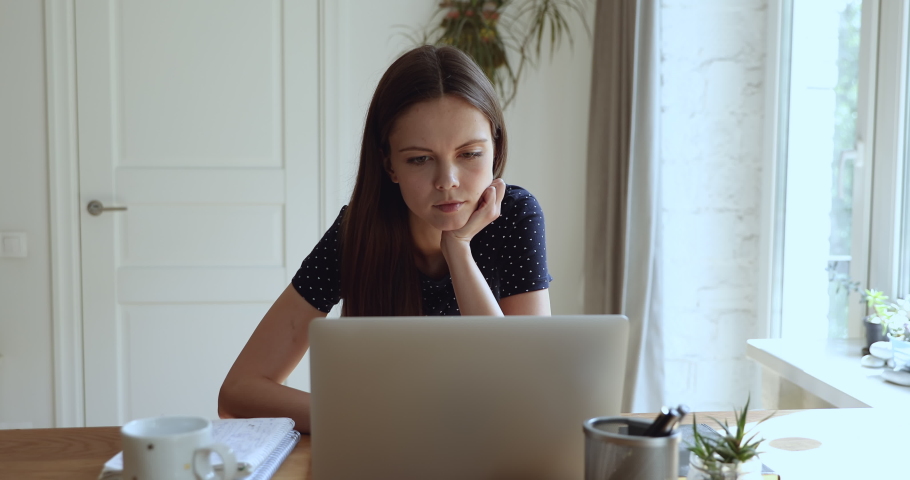 Serious focused pensive student girl freelancer woman sitting at desk in front of laptop thinking search solution looking out the window feels tired or unmotivated while studying or working at home Royalty-Free Stock Footage #1055702600