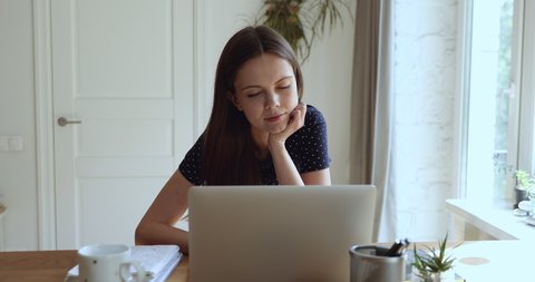 Serious focused pensive student girl freelancer woman sitting at desk in front of laptop thinking search solution looking out the window feels tired or unmotivated while studying or working at home