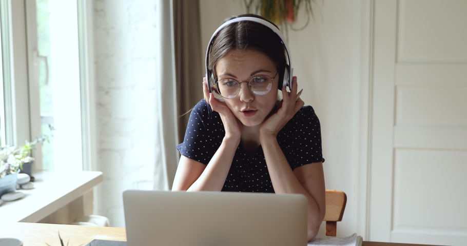 Student sit at table use headphones wear eyeglasses talk with tutor by online videocall conference app. English language practice discuss common project with schoolmate distantly work together concept Royalty-Free Stock Footage #1055702729