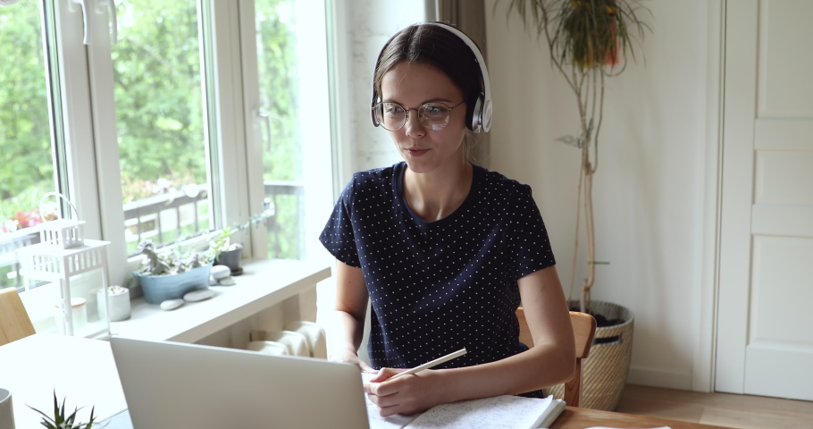 Student girl wear eyewear headphones use pc noting helpful info learn subject talks with mate by videocall application. Distant communication study process, self-education, gain new knowledge remotely Royalty-Free Stock Footage #1055702735