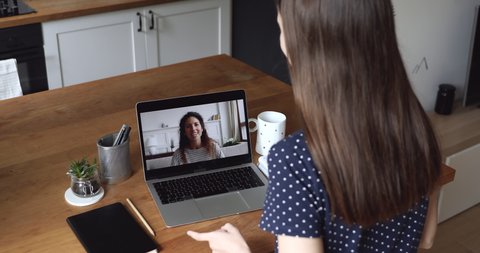 Services provider and client distant negotiation activity, women best friends communication via videoconference application, over female shoulder laptop screen view. Video call interaction concept - Βίντεο στοκ