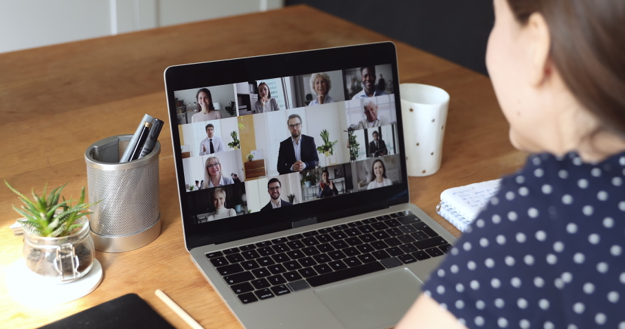 Different age ethnicity people engaged in video call communication, laptop screen view over woman shoulder sit at desk looks at pc involved in conversation. Internet space virtual visual talk concept Royalty-Free Stock Footage #1055702777