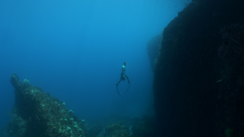 Free Diver Man swims up and ascends to surface of calm and peaceful ocean. Epic outdoor adventure concept.