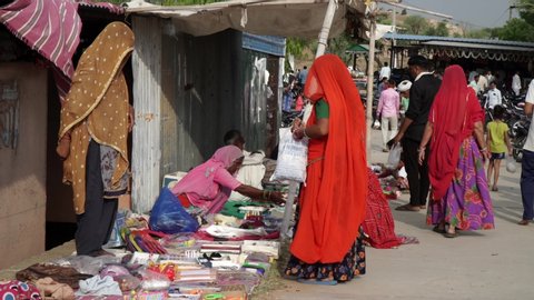Dadar, Jaipur, Rajasthan, India - July 08, 2020: Indian village women selling toys item to the kids at street shop during fair program, Indian Village fair