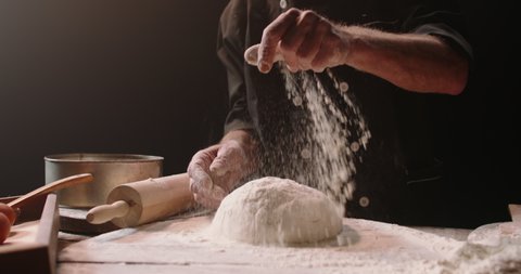 Experienced elderly caucasian chef is putting flour and kneading dough, using traditional recipes, pensioneer enjoying his hobby after retirement, isolated on black background 4k footage
