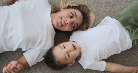 Loving mother and son having fun lying on the floor at home : vidéo de stock