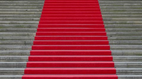 Cinemagraph of walking up red carpet over grey concrete stairs, close up, low angle view