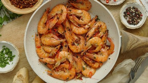 Roasted Prawns on frying pan served on white wooden cutting board. Rusty wooden background. Seafood lunch or dinner concept. Top view, flat lay.