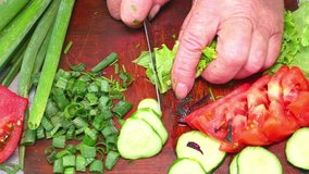 Slicing green lettuce with a knife on a cutting board. Green vegetable salad. Vegetable. Cook. Home kitchen. Vegetarian food. Recipe. Promotional video. Video. Hands of a man. Vitamins