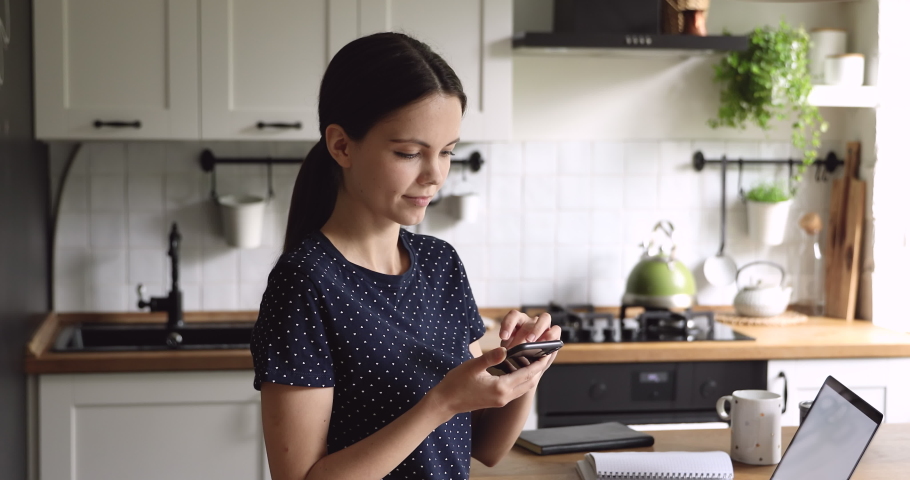 Woman spend time on kitchen hold phone receives long-awaited sms great news makes Yes gesture feels incredible happy, scream with joy laughing enjoy moment of personal achievement goal succeed concept Royalty-Free Stock Footage #1055716145