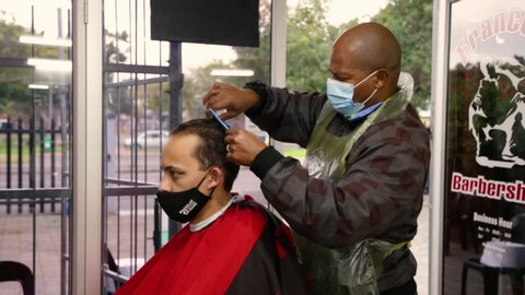 Cape Town, South Africa - July 2020: Front Line Worker, South African Barber Working During Lock Down, Wearing Protective Mask, Covid 19, Corona Virus Pandemic in Africa. Hair cut Ban Lifted.
