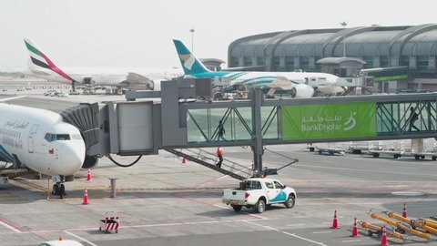 Muscat, Oman - May 6, 2019: Airport passengers boarding on a plane, people walking through jet bridge. Also termed jetway, jetwalk, airgate, gangway, aerobridge, airbridge, skybridge, airtube, or its