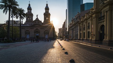 Zoom out timelapse view of sun setting behind historical landmark Santiago Metropolitan Cathedral at Plaza de Armas square in downtown Santiago, the capital and largest city in Chile, South America. 