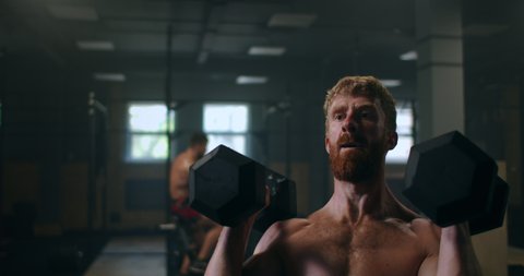 perseverance and work during physical activity training, a man overcomes difficulties by lifting heavy dumbbells over his head. the concept of the path to success goal achievement