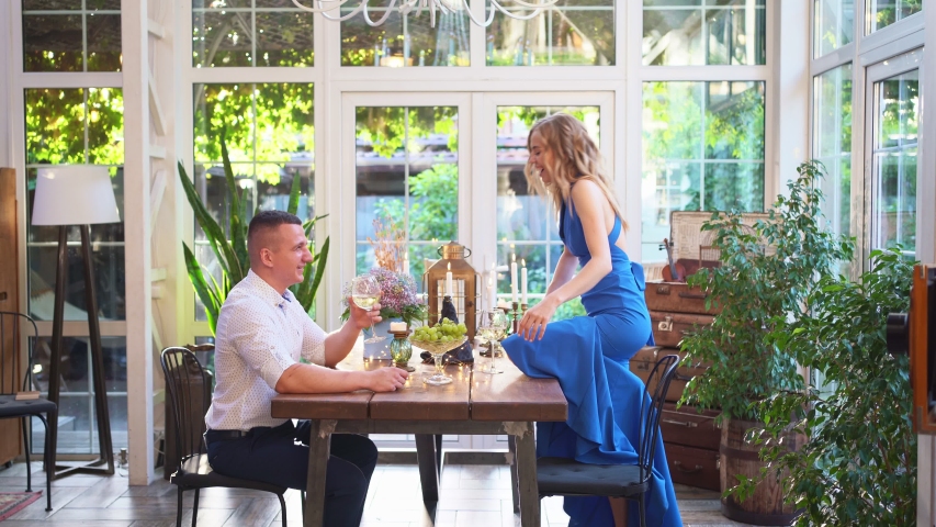 romantic dinner for a couple in love. girl with a glass of wine stands on the table to kiss her boyfriend.