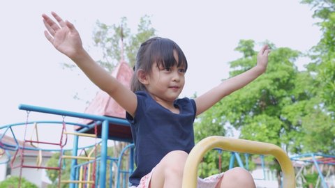 Cute asian litte girl is happy to playing the seesaw and acting like flying bird and smiling, concept of outdoor activity for kid development and learn through play activity.
