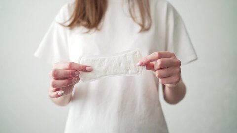 A woman with a period holds a white pad. Taking care of women's health. Hygiene during menstruation