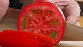 the cook slices delicious tomatoes on a wooden Board.4K video.