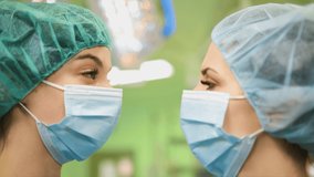 Two female doctors pray in medical face masks and caps look at each other - Powered by Shutterstock - Get 15% off with code: PIKWIZARD15