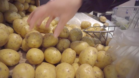 Picking of potatoes on the shelf in the grocery in Helsinki Finland and packing it on the plastic bag