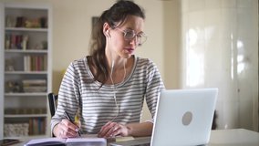 woman studying isolated in home using laptop. Spbd college student listening to professor teacher with headphones. e-learning distant during coronavirus pandemic quarantine. girl take notes