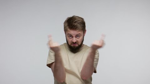 Crazy hooligan bearded man showing around his middle fingers, demonstrating protest with impolite rude gesture of disrespect, rejecting communication. indoor studio shot isolated on gray background