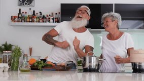 Happy senior couple dancing while cooking together at home - Mature people having fun preparing the lunch - Joyful elderly lifestyle and food nutrition concept - Slow motion - Powered by Shutterstock - Get 15% off with code: PIKWIZARD15