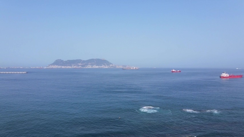 The British Rock of Gibraltar in the background on a cloudless summer day from the air. A few merchant ships can be seen in the foreground.