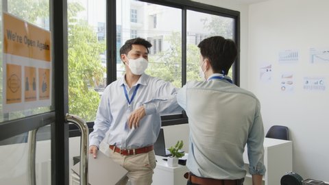 Asian businessman greeting with elbow bump or shaking elbow in working office to avoid touching due to infection of coronavirus covid-19, new normal life and social distancing concept