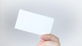 White business card sheet in hand on a gray background. A hand holds a business card and disappears. Business concept. Video clip hd