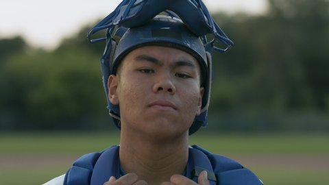 Back catcher for a professional baseball team looks on to the camera with focus and determination in his eyes. Portrait of a baseball player. Shot in 4k 