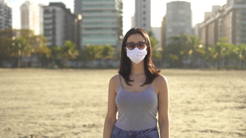 woman wearing face mask and sun glasses for corona virus prevention on the beach. Loosen restriction, reopen
 Royalty-Free Stock Footage #1055820047