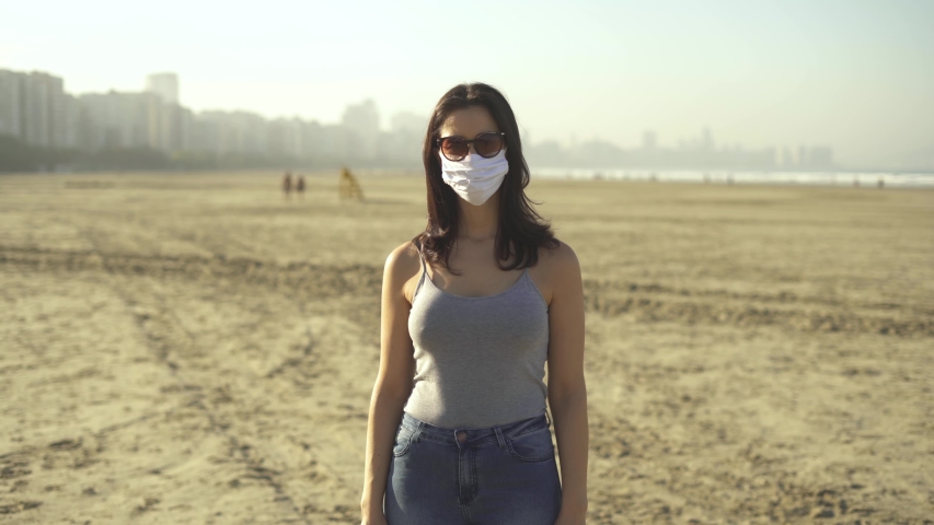 woman wearing face mask and sun glasses for corona virus prevention on the beach. Loosen restriction, reopen
 Royalty-Free Stock Footage #1055820089
