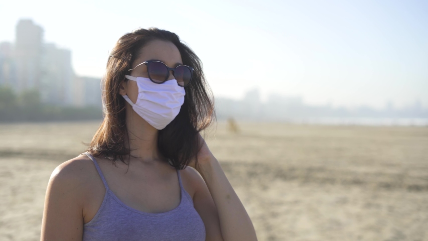 woman wearing face mask and sun glasses for corona virus prevention on the beach. Loosen restriction, reopen
 Royalty-Free Stock Footage #1055820356