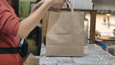 pickup of food from a restaurant in a craft paper bag, a girl picks up an order from a restaurant
