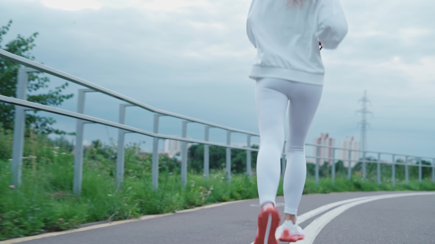 Beautiful blonde girl in a white top and leggings Jogging in the Park on a Sunny day