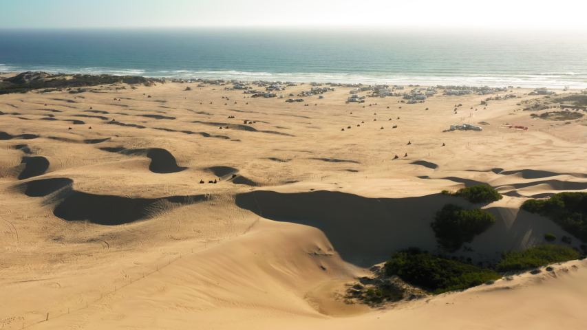 Drone flying over the ATVs and Buggy playground. Scenic wild desert nature landscape with blue sky. Beautiful aerial at sunset. 4K aerial view on the sand hills meeting the Pacific ocean, California