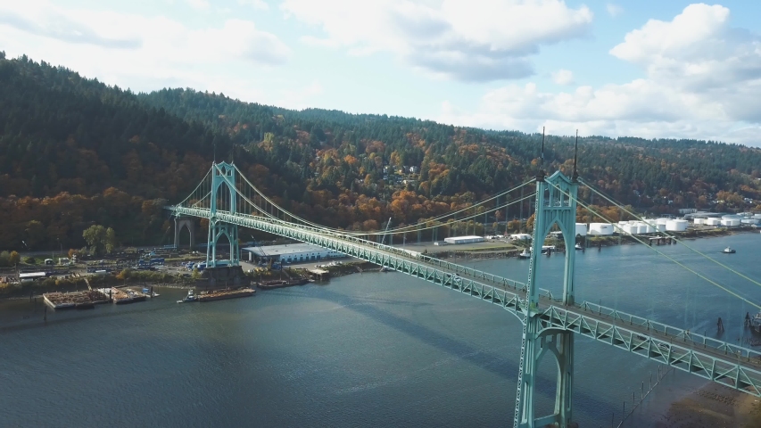 Beautiful 4k aerial footage of the St. Johns Bridge in Portland - Oregon while autumn with colorful yellow and orange forest in the background.