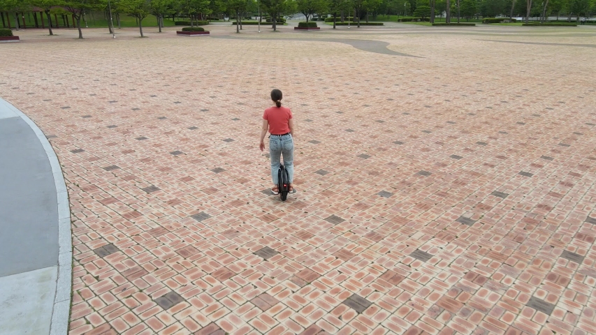 Young girl rides an electric unicycle rear view.