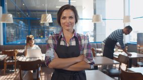 Portrait of cheerful waitress in apron smiling at camera with hands crossed standing in cafe. Smiling young staff or small cafe business owner entrepreneur looking at camera, posing in cafeteria - Powered by Shutterstock - Get 15% off with code: PIKWIZARD15
