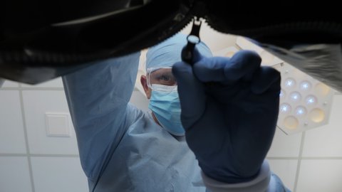 Doctor pathologist closes the plastic mortuary bag with a dead body inside. Hospital morgue, a corpse in a black plastic bag. Low angle view, conceptual footage