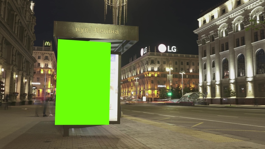 Billboard with a chroma key green screen on n bus stop at night. Time Lapse. Royalty-Free Stock Footage #1055871221