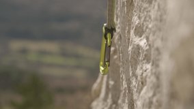 SLOW MOTION, CLOSE UP, DOF: Unrecognizable female rock climber clips her belay rope into a carabiner. Fit woman top roping loops her rope into a safety carabiner. Girl top roping up challenging cliff