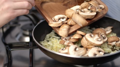 Adding sliced mushroom into risotto in a frying pan. Concept of adding chopped mushroom ingredient into a pan on a gas stove in 4K.