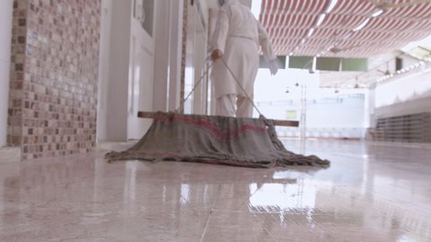 Muslim man sanitizes each row of mosque with traditional cloth wiper 