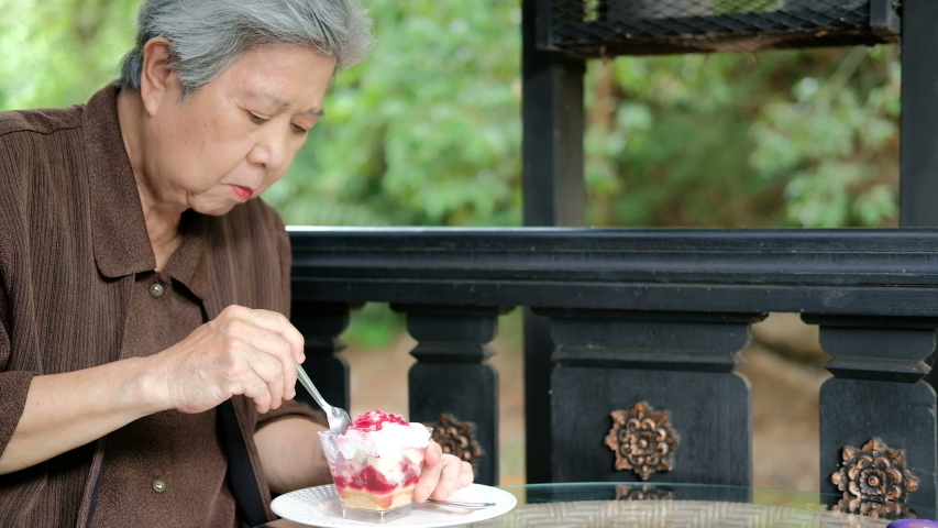 old asian elderly senior elder woman eating strawberry cream cheesecake at restaurant. mature retirement lifestyle